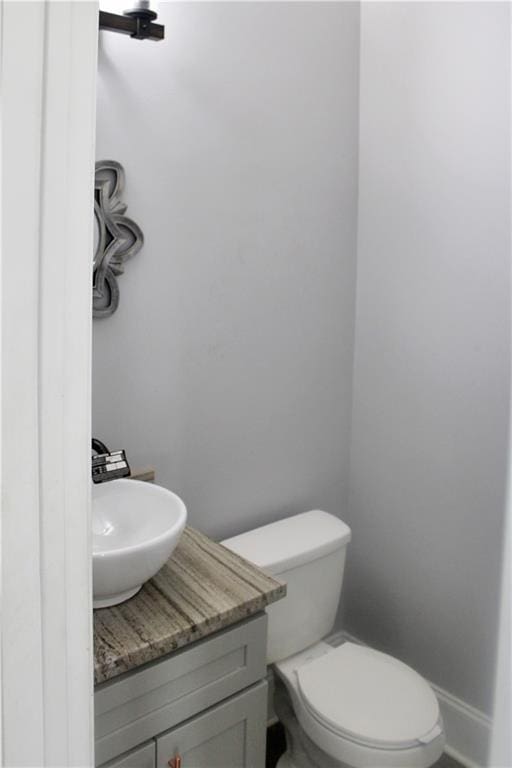 bathroom featuring toilet, baseboards, and vanity