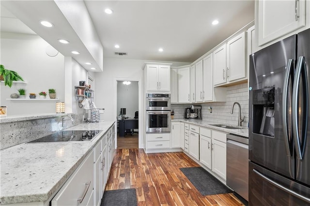 110 Rue Acadian, Belle Chasse, LA 70037 - kitchen with dark wood finished floors, stainless steel appliances, white cabinetry, a sink, and light stone countertops