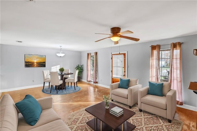 living area featuring a ceiling fan and baseboards