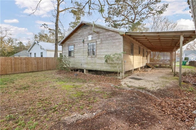 back of house with fence and a carport