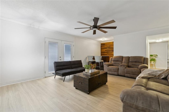 living area with light wood-style floors, baseboards, crown molding, and french doors