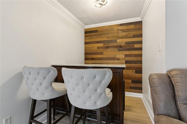 dining room with a textured ceiling, wood walls, wood finished floors, and crown molding