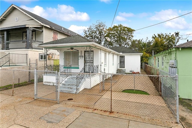 shotgun-style home with a fenced front yard, a gate, covered porch, and roof with shingles