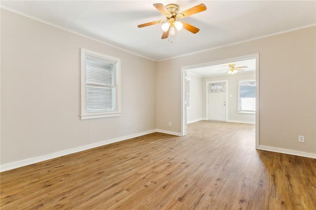 unfurnished room with ornamental molding, a ceiling fan, baseboards, and wood finished floors