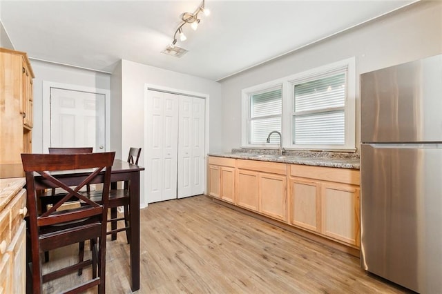 kitchen featuring visible vents, light wood-style flooring, light brown cabinetry, freestanding refrigerator, and a sink