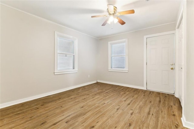 spare room featuring light wood-style floors, a healthy amount of sunlight, ceiling fan, and baseboards