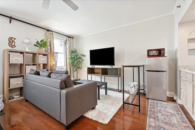 living room featuring dark wood-style floors, ceiling fan, baseboards, and crown molding