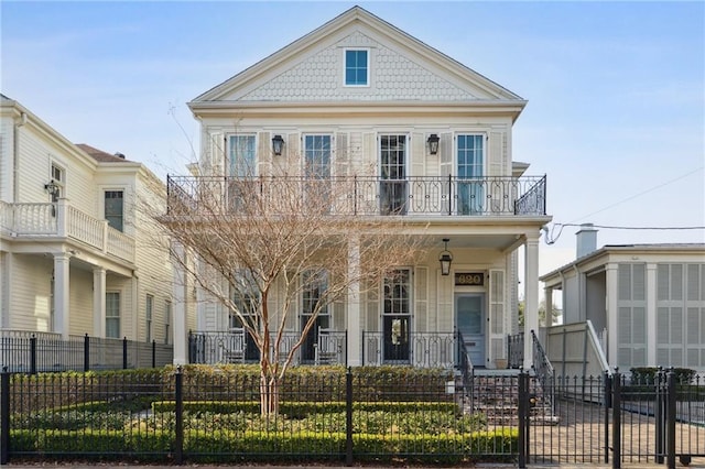 view of front of house featuring a balcony, a fenced front yard, and a porch