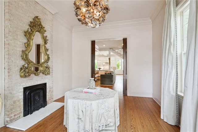 dining area featuring ornamental molding, a fireplace, light wood-style flooring, and baseboards