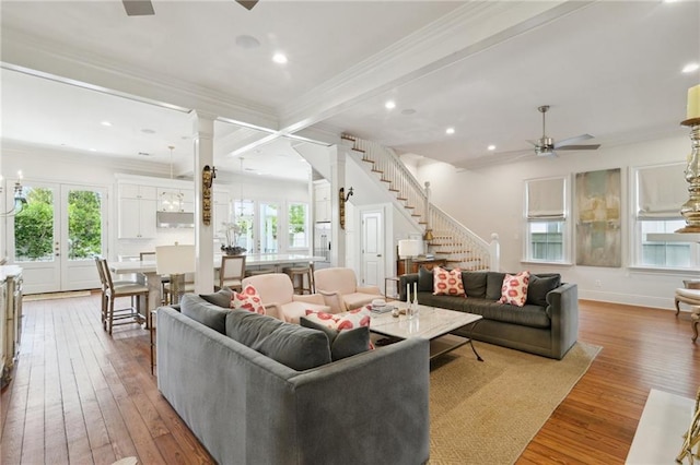 living area with stairs, french doors, wood finished floors, and a healthy amount of sunlight