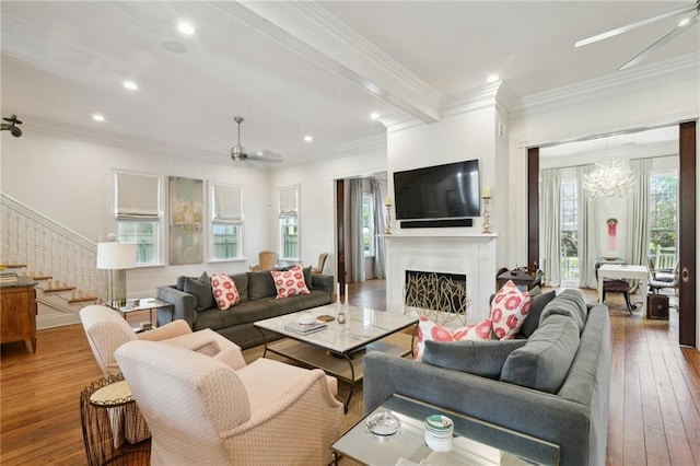 living room featuring stairway, wood finished floors, crown molding, a fireplace, and recessed lighting