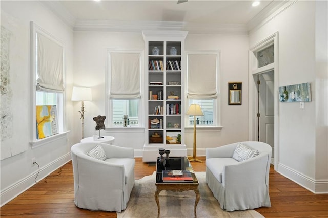 living area featuring wood finished floors, a wealth of natural light, and crown molding