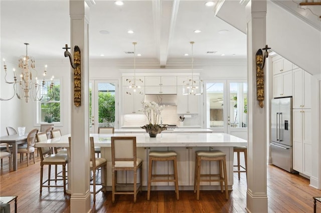 kitchen with a spacious island, a kitchen breakfast bar, stainless steel built in refrigerator, and decorative light fixtures