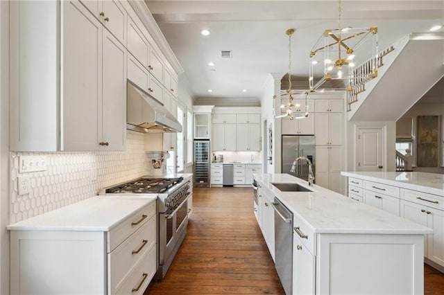 kitchen featuring hanging light fixtures, white cabinets, a sink, high quality appliances, and a large island with sink