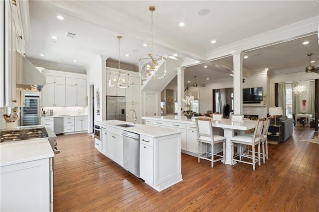 kitchen with stainless steel appliances, a spacious island, white cabinets, open floor plan, and light countertops