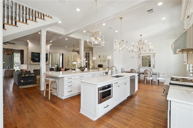 kitchen featuring stainless steel appliances, light countertops, open floor plan, white cabinets, and a large island with sink