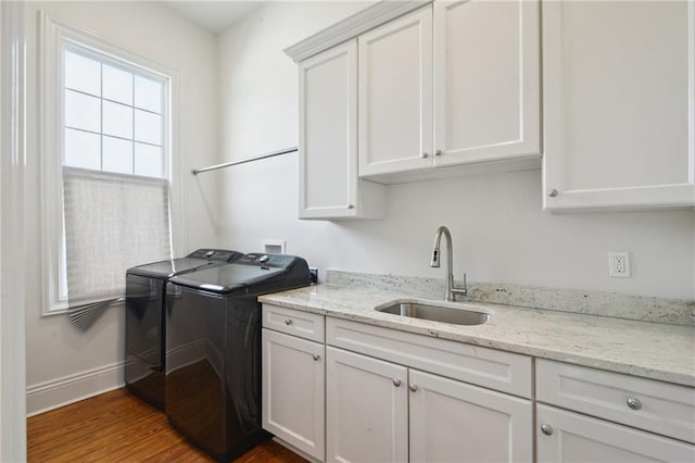 laundry area featuring cabinet space, baseboards, dark wood finished floors, washer and dryer, and a sink