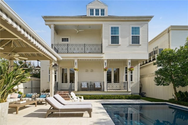 back of house with a fenced in pool, a patio, a ceiling fan, fence, and a balcony