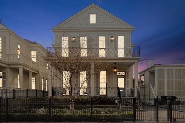 view of front facade with a balcony and a fenced front yard