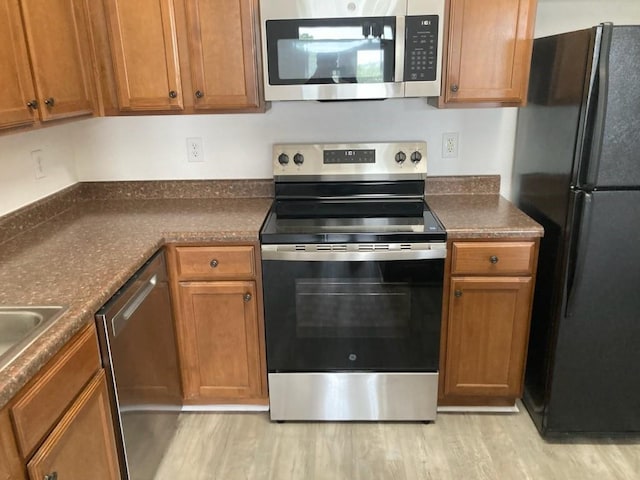 6765 Corporate Blvd Unit 2310, Baton Rouge, LA 70809 - kitchen featuring stainless steel appliances, light wood-style flooring, dark countertops, and brown cabinetry