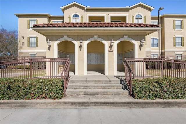 view of front of home with a fenced front yard, a porch, a tiled roof, and stucco siding