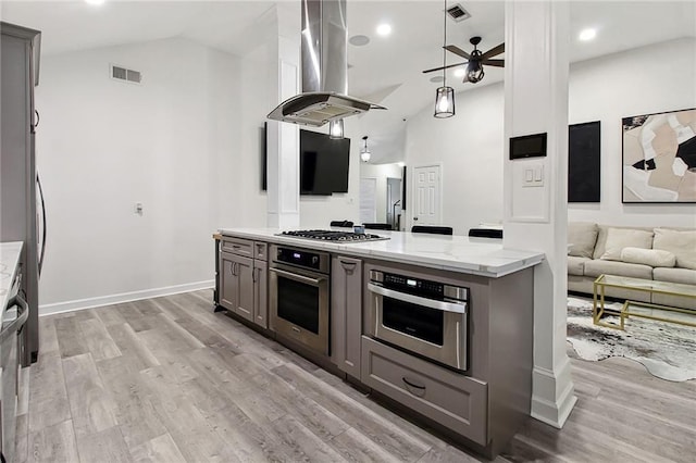 kitchen with light stone counters, stainless steel appliances, light wood-style flooring, gray cabinetry, and island range hood