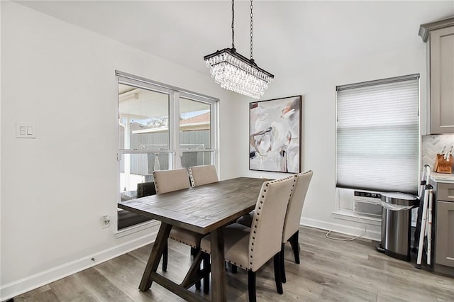 dining room featuring light wood-type flooring, cooling unit, baseboards, and an inviting chandelier