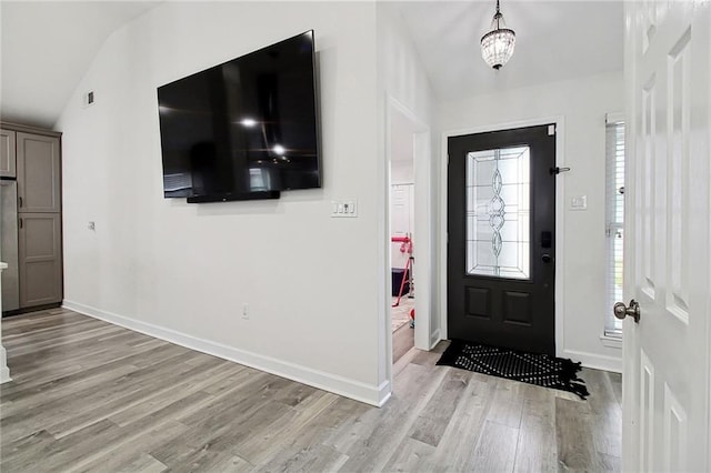 foyer entrance with light wood-type flooring, lofted ceiling, and baseboards