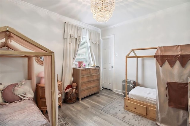 bedroom featuring light wood-style flooring, ornamental molding, and a chandelier