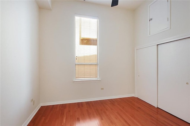 unfurnished bedroom featuring ceiling fan, wood finished floors, a closet, and baseboards