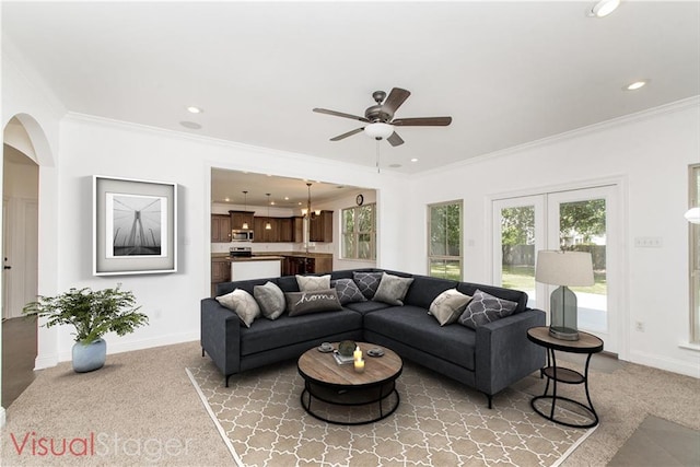 living room featuring ornamental molding, arched walkways, baseboards, and light carpet