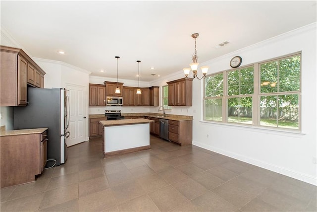 kitchen featuring a center island, stainless steel appliances, baseboards, and ornamental molding