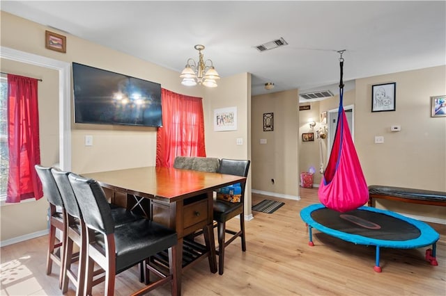 dining room featuring baseboards, an inviting chandelier, visible vents, and light wood-style floors