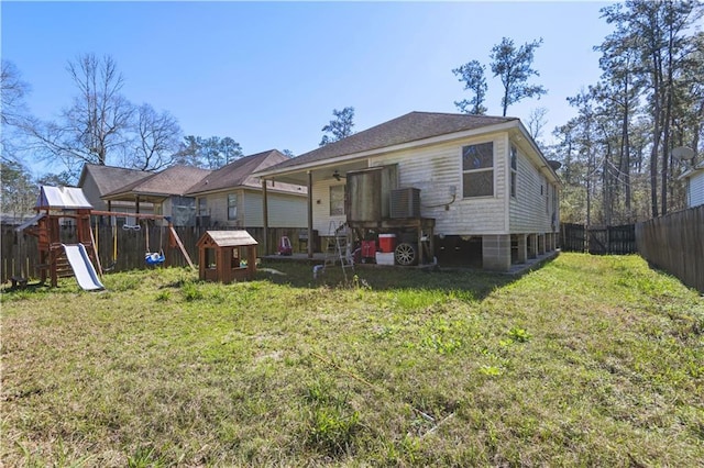 back of house with a fenced backyard, a lawn, and a playground