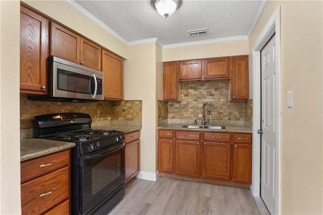 kitchen featuring a sink, visible vents, brown cabinets, stainless steel microwave, and gas stove