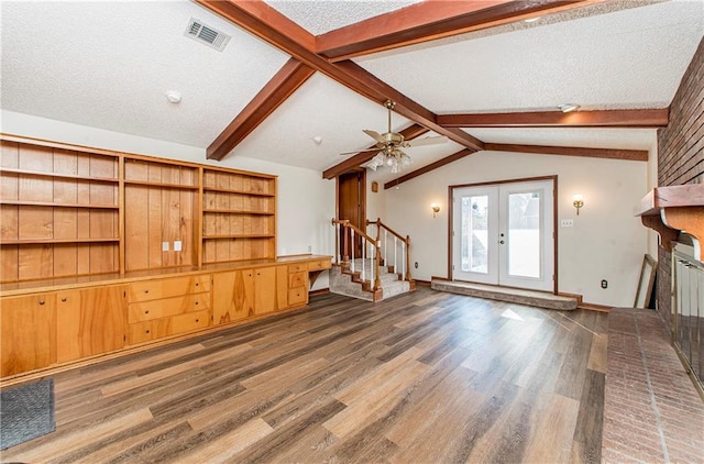 unfurnished living room featuring lofted ceiling with beams, dark wood-type flooring, visible vents, french doors, and stairway