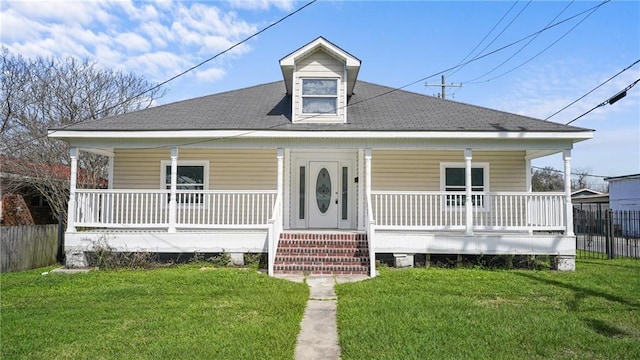 view of front facade with a porch, a front yard, and roof with shingles