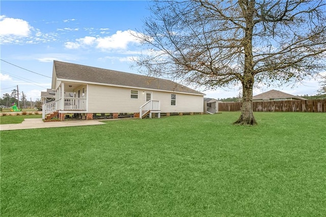 rear view of property featuring a shingled roof, fence, and a lawn