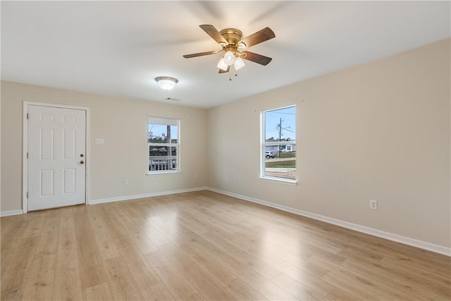 empty room with light wood finished floors, plenty of natural light, and baseboards