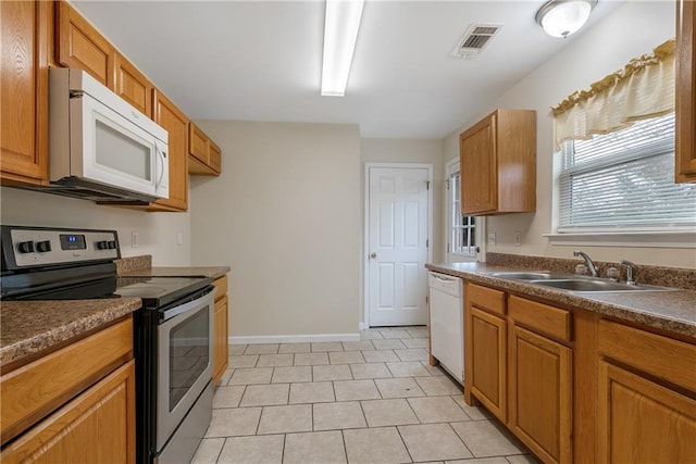 kitchen featuring brown cabinets, dark countertops, visible vents, a sink, and white appliances