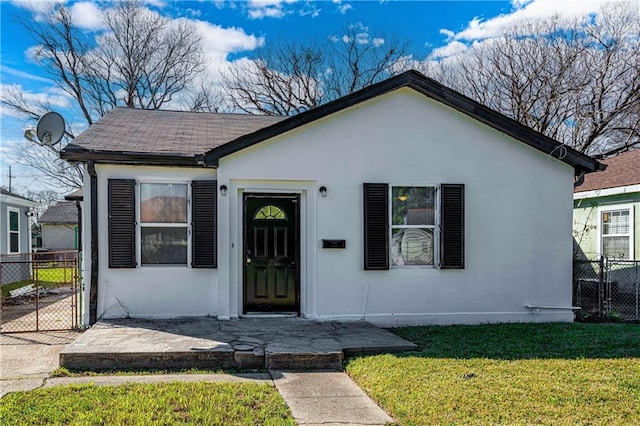 bungalow-style home with fence, a front lawn, and stucco siding