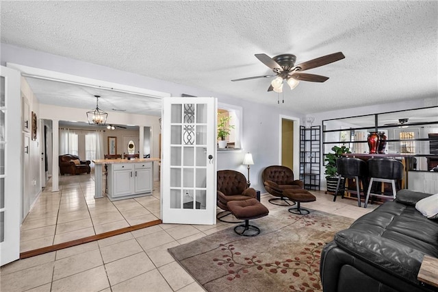 living room featuring ceiling fan with notable chandelier, a textured ceiling, and light tile patterned floors