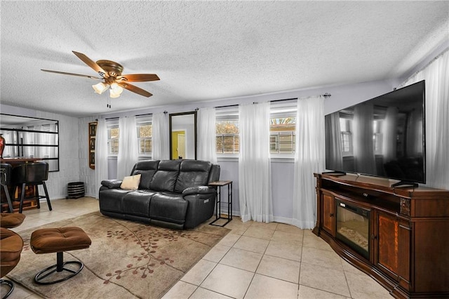 living area featuring a ceiling fan, light tile patterned flooring, a textured ceiling, a bar, and baseboards