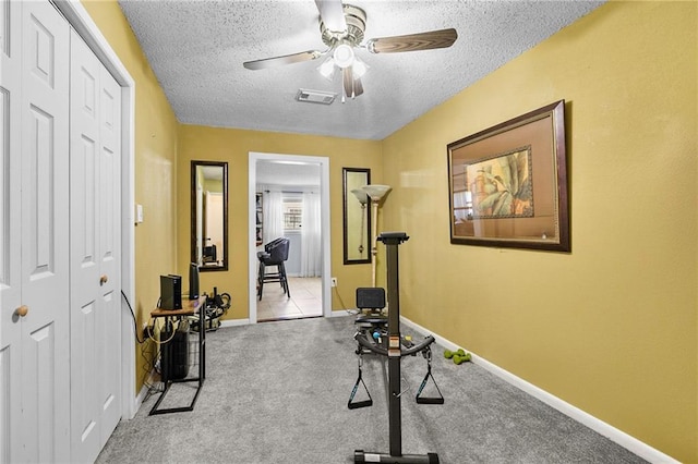 exercise area with a textured ceiling, light carpet, a ceiling fan, visible vents, and baseboards