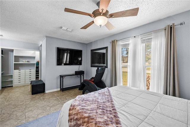 bedroom with a textured ceiling, tile patterned flooring, visible vents, baseboards, and a ceiling fan