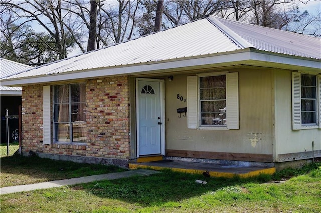 view of front of house featuring brick siding and metal roof