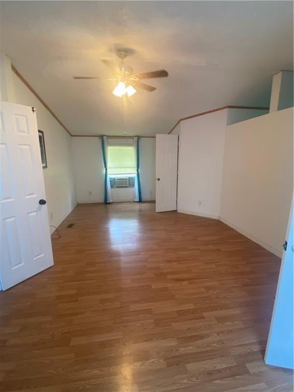 empty room featuring ceiling fan, cooling unit, vaulted ceiling, and wood finished floors