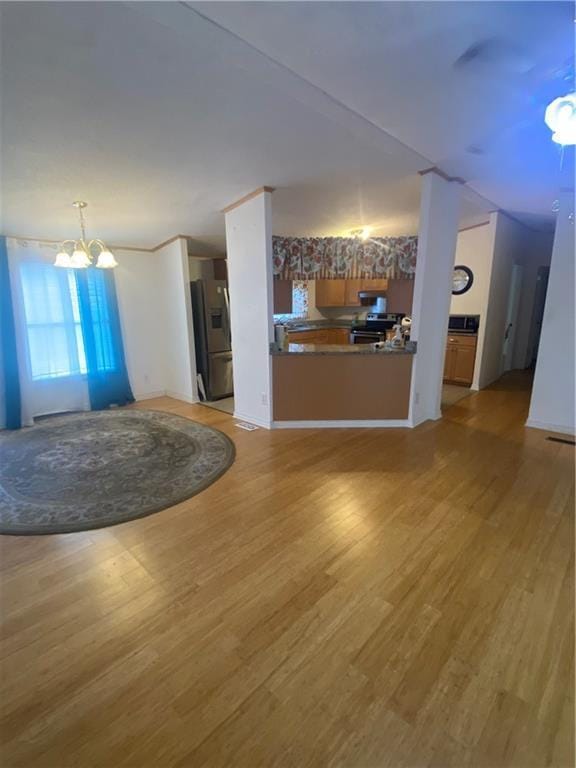 unfurnished living room with a chandelier and light wood-type flooring