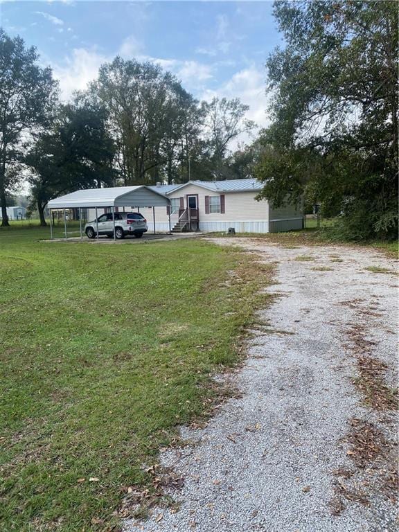 manufactured / mobile home with a carport, driveway, and a front lawn