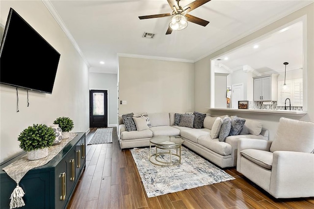 living area with visible vents, ceiling fan, dark wood-style flooring, crown molding, and recessed lighting